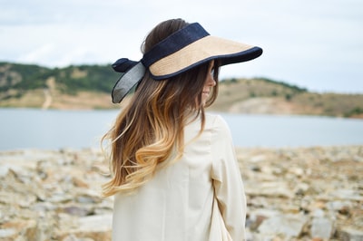 戴着遮阳帽站在湖边的女人